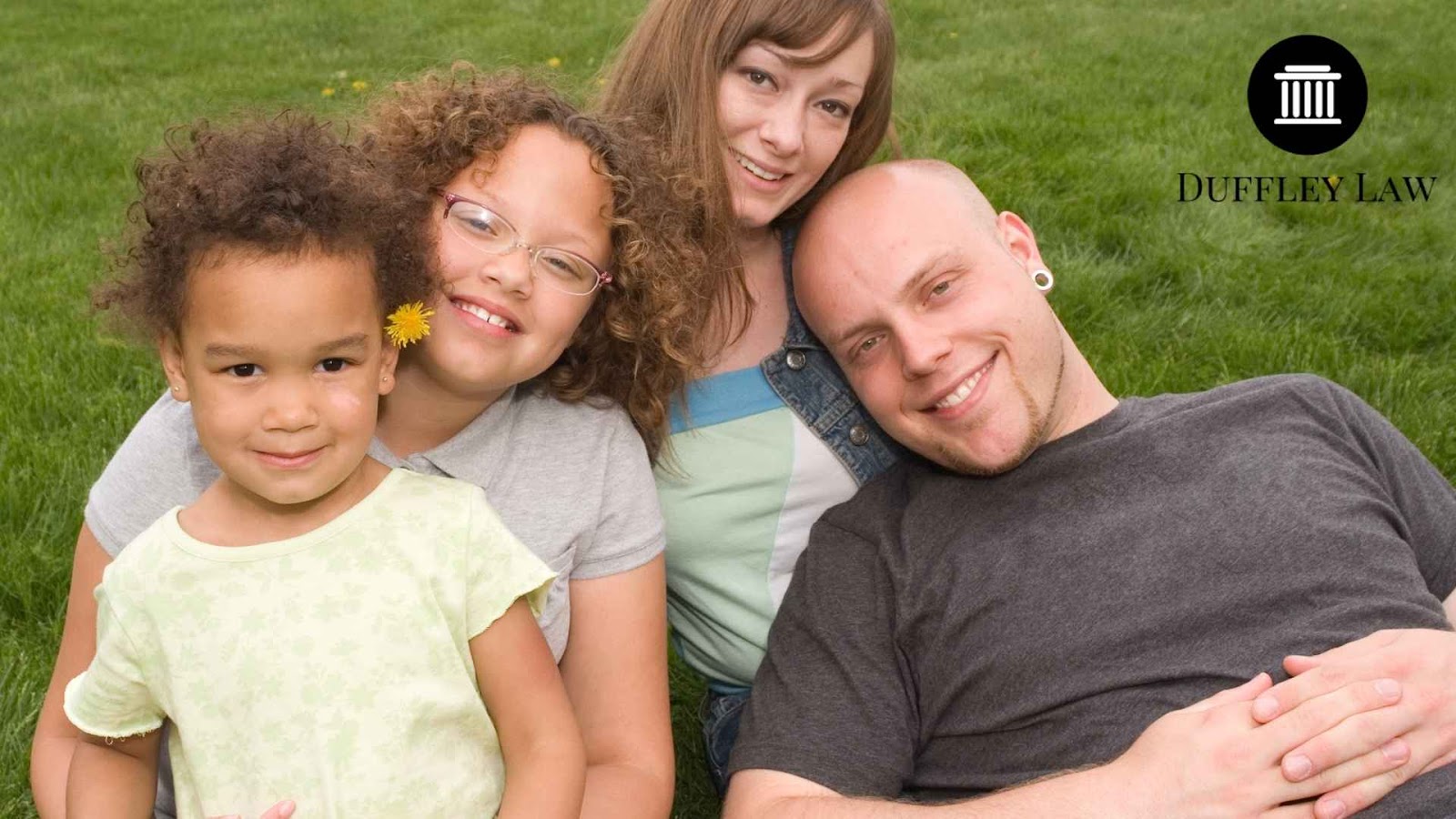 Happy blended family sitting together on grass.