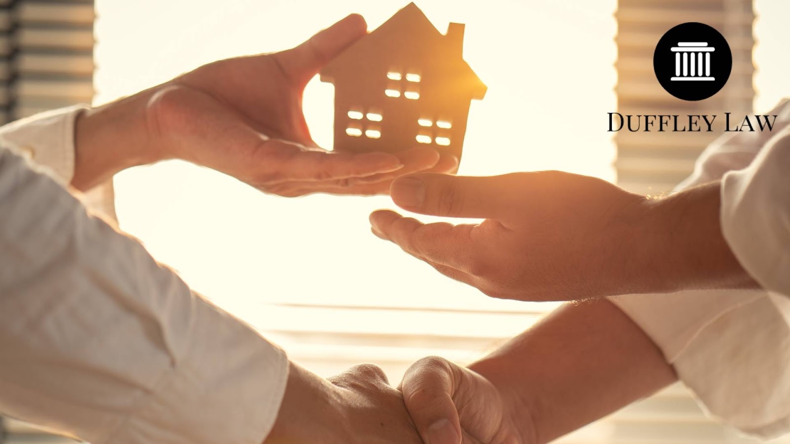 close-up of people exchanging a minuature house and shaking hands at the same time