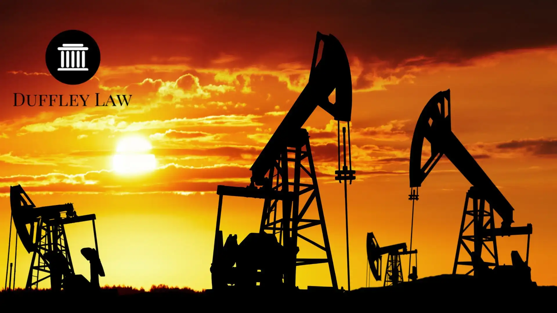 Oil pumpjacks silhouetted against orange sunset sky